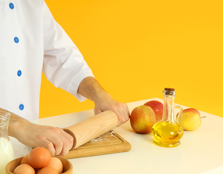 young male chef cooking on yellow background